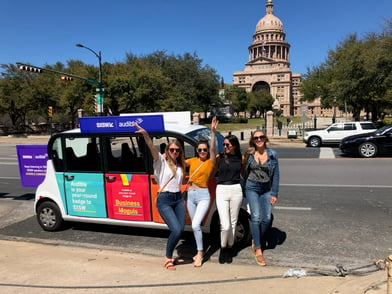 four woman posing with an audible branded circuit car in front of capitol building in austin
