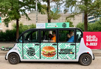 Four riders smiling from a burger king branded circuit vehicle