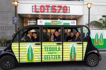 A driver and four riders smile from a Hornitos branded Circuit car.