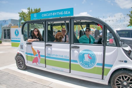 Passengers and a happy dog smile from a Circuit-by-the-sea vehicle