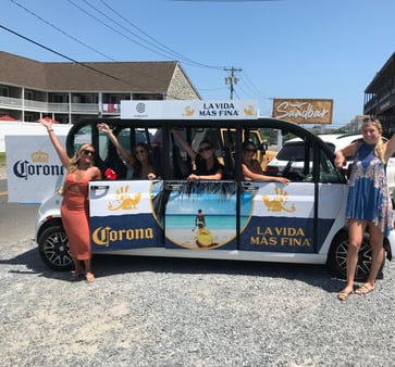 Women waving from a Corona-branded Circuit car