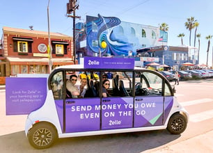 Circuit riders smiling from a zelle-branded vehicle