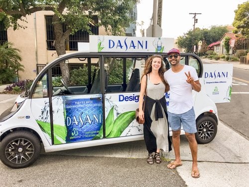 Man and woman smiling in front of a Dasani branded Circuit car